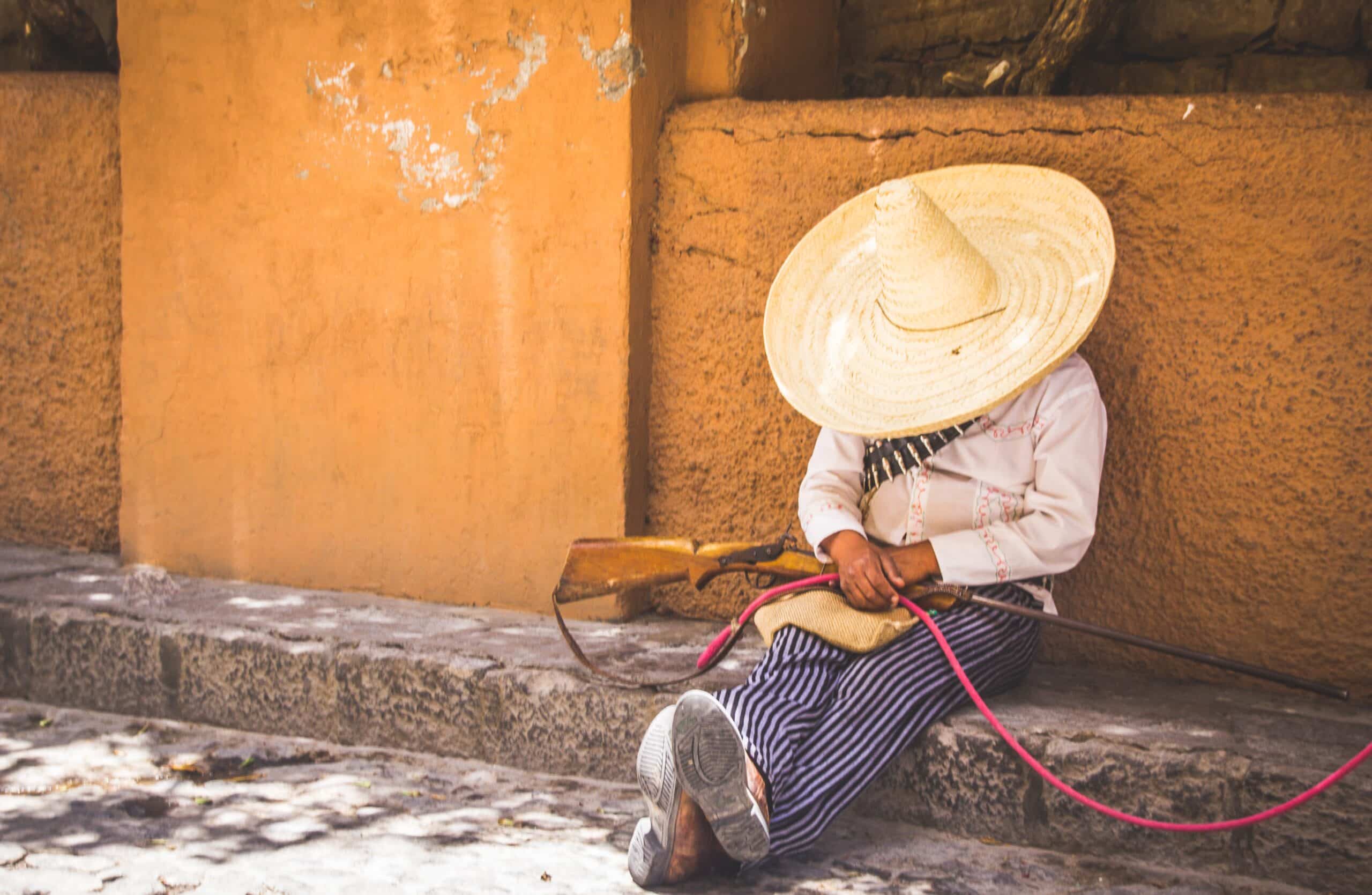 un hombre descansa en ropas mexicanas a la sombra en una calle