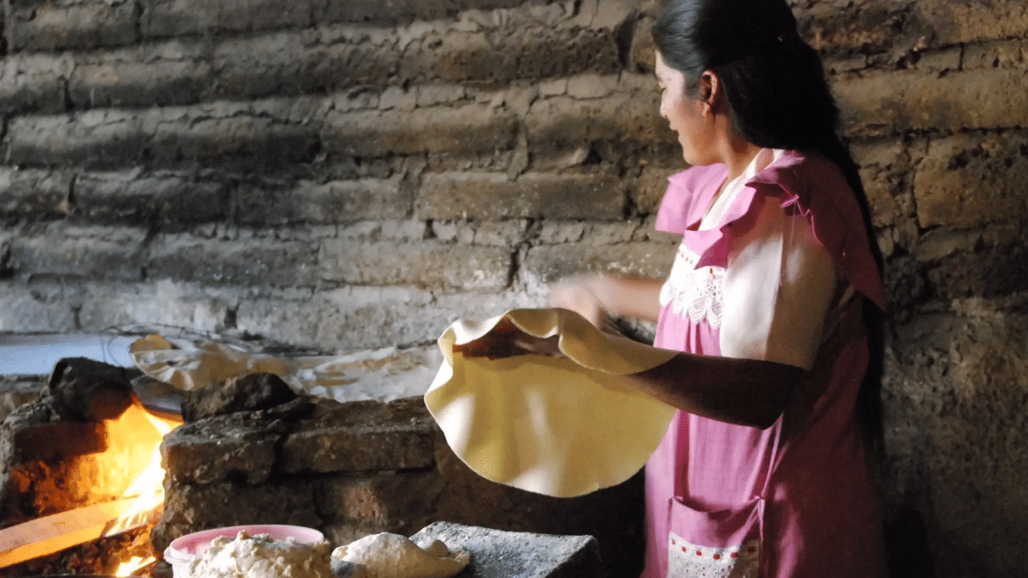 Mujer cociendo una tortilla en un comal