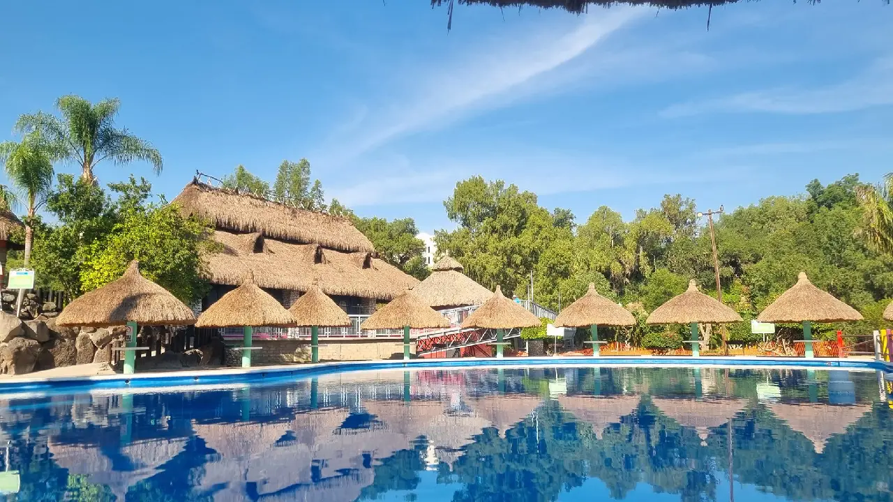 El parque cuenta con albercas termales, toboganes, áreas infantiles y amplias zonas verdes donde los visitantes pueden descansar o disfrutar del sol.